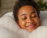 Smiling person relaxing in bathtub with bubbles