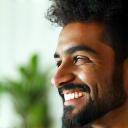Profile of Arjun, smiling in bathroom with plants